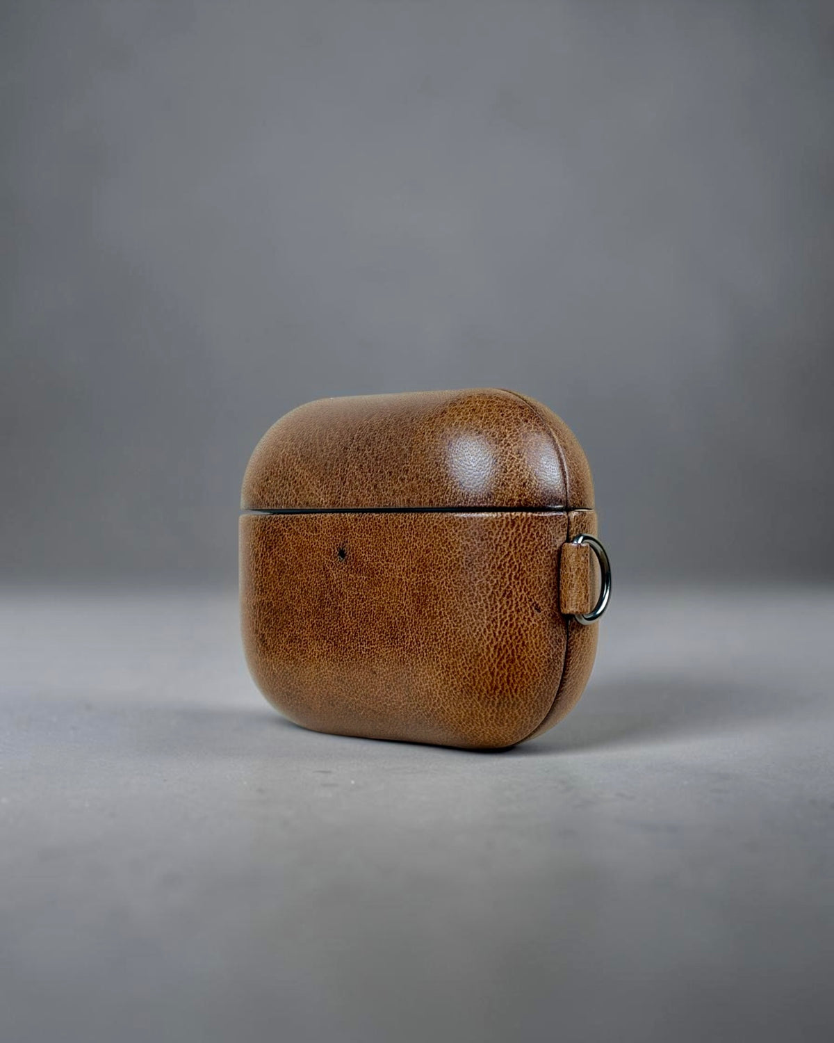 AirPods Pro 3 leather case in Brunello Brown, three-quarter view with key ring #Color_Brunello Brown