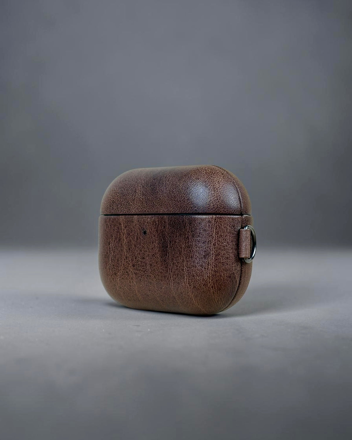 AirPods Pro 3 leather case in Castagna Marrone, three-quarter view with key ring #Color_Castagna Marrone