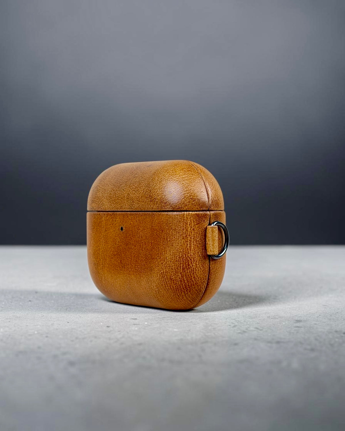 AirPods Pro 3 leather case in Siena Gold, three-quarter view with key ring #Color_Siena Gold